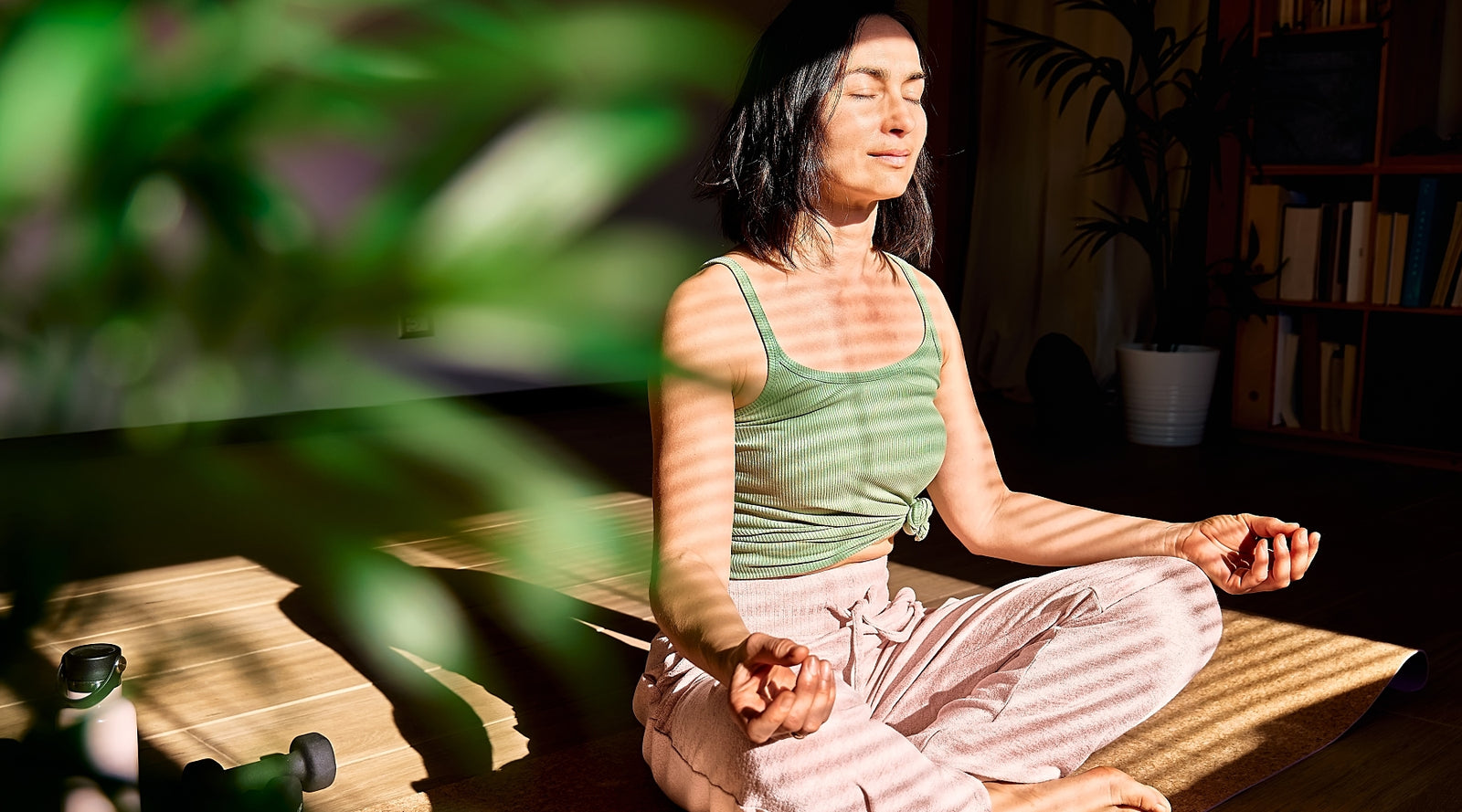 A person meditates with crossed legs on the floor of their apartment