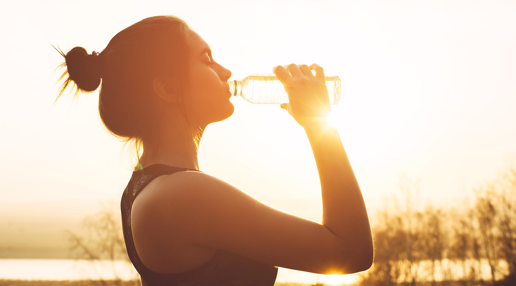 Woman drinking water after a workout to support detoxification