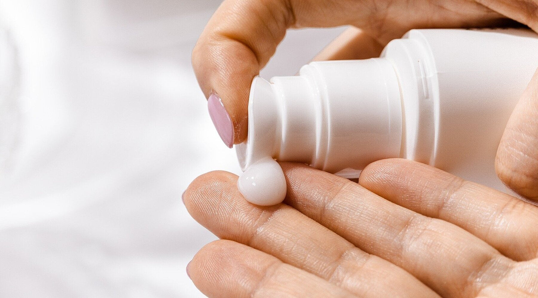 A hand applies a pump of moisturizer