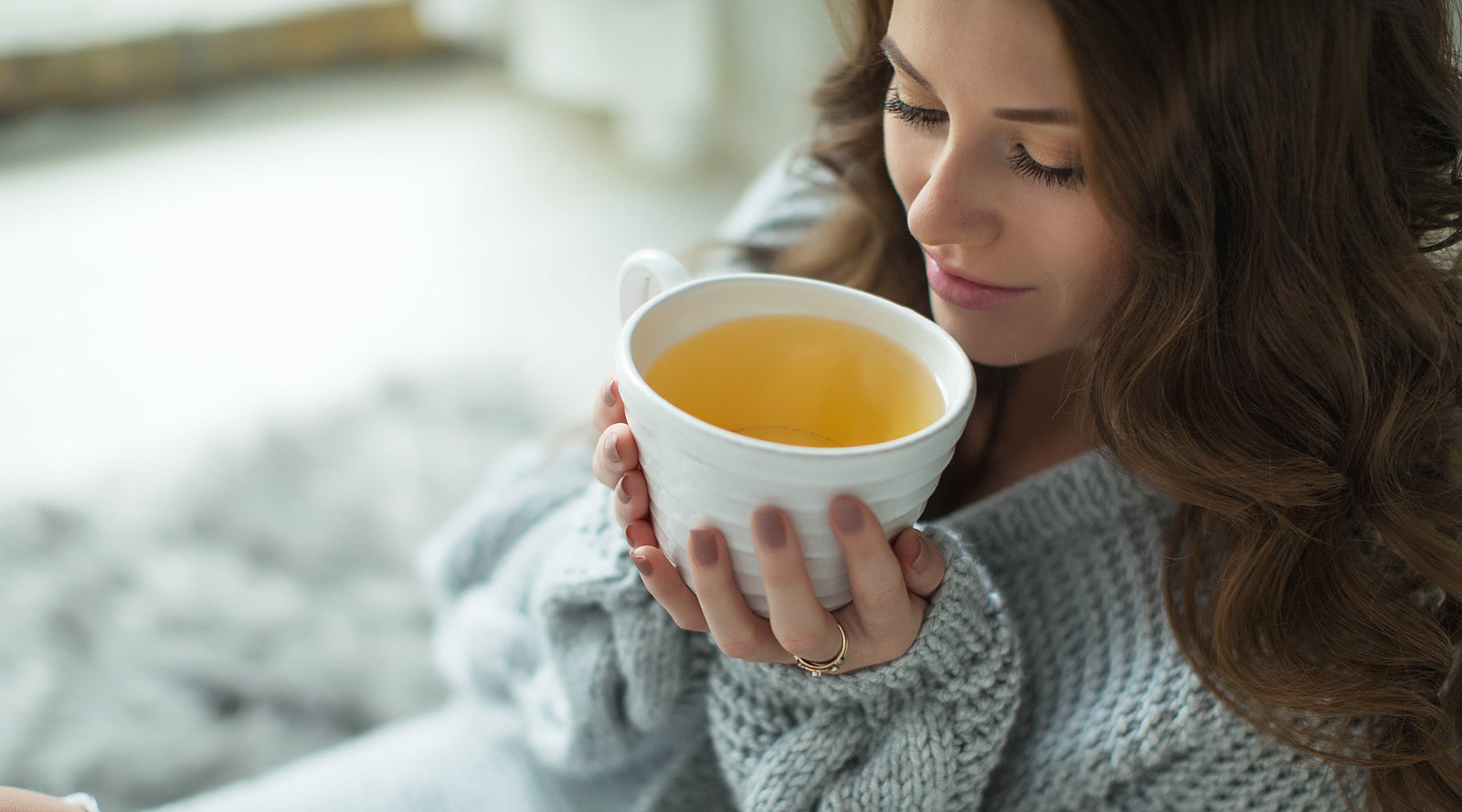 Woman wrapped in tan shawl holding a blue mug