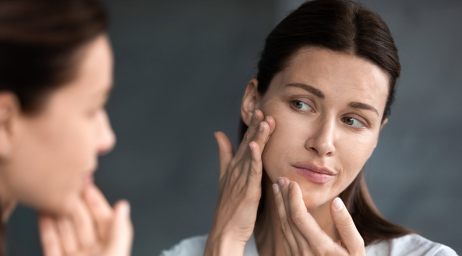 Woman looking in the mirror at her skin