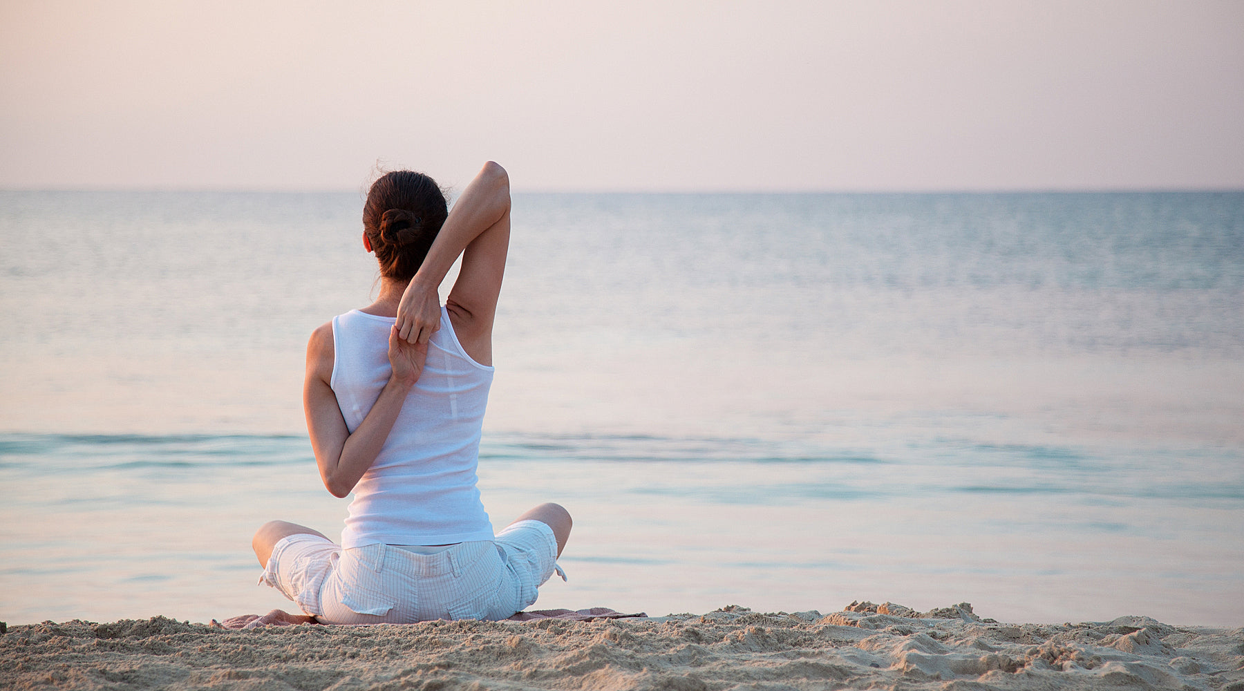 Young woman doing yoga on beach at dawn
