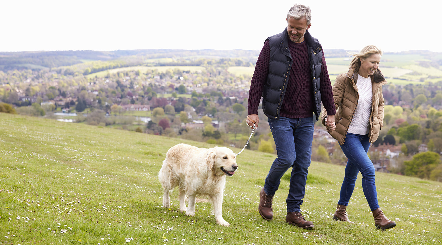 A couple walk their dog in the park.