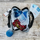 EquiLife Lunch Cooler open on a wooden table with a shaker bottle, grapes, an ice pack, and Daily Nutritional Support packets